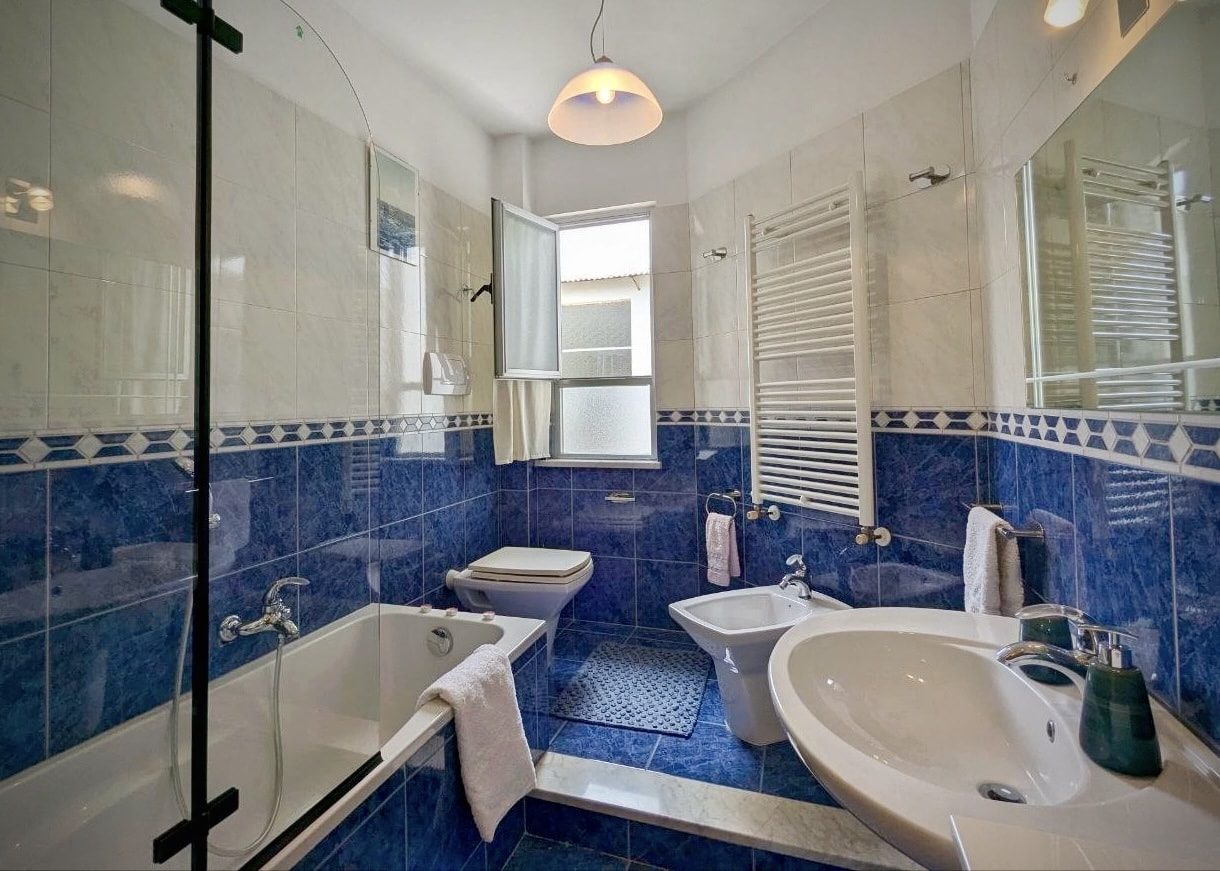 Blue-tiled shared bathroom with bath and walk-in shower
