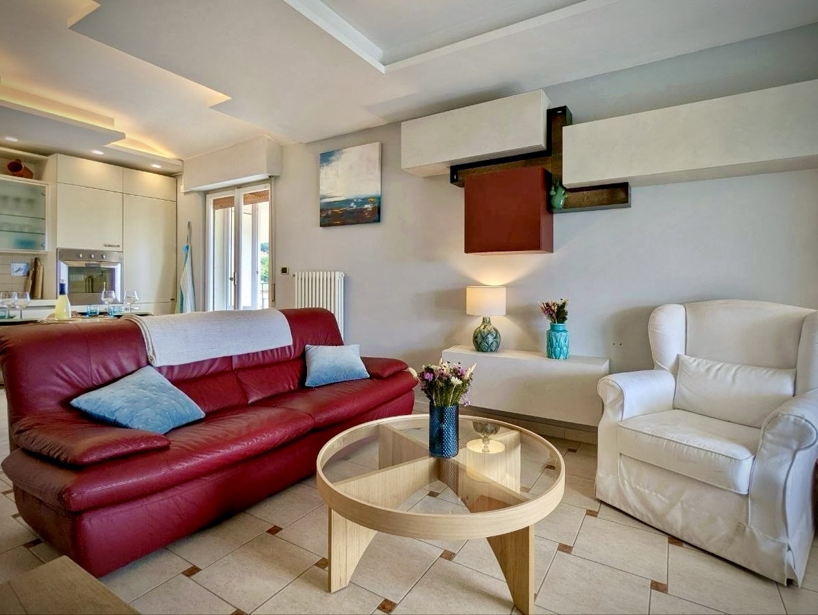Lounge with burgundy leather sofa, open to the kitchen
